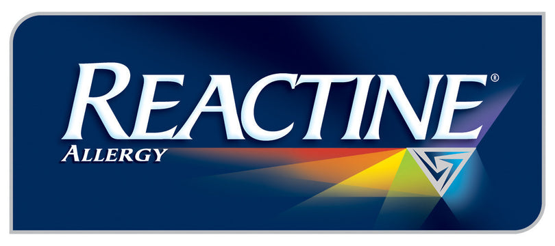 The REACTINE logo features bold white text on a dark blue background, with a rainbow-colored beam emerging from a triangular symbol beneath the word, representing fast and broad-spectrum allergy relief.