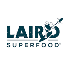 The Laird Superfood logo shows bold text with a surfer riding a wave as the letter “I,” holding a leafy branch, symbolizing strength and plant-based nutrition.