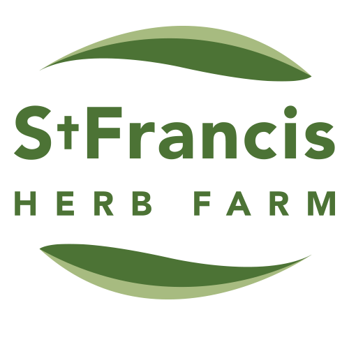 The St. Francis Herb Farm logo features the brand name in bold green letters, with “St. Francis” above “Herb Farm,” framed by two curved green leaf shapes above and below, symbolizing natural wellness and plant-based healing.