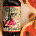 Barefoot Venus Ruby Red argan body oil product label close up with pink grapefruit slices and almond nuts.