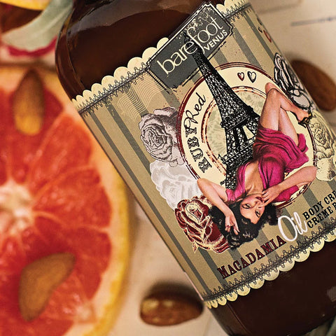 Barefoot Venus Ruby Red macadamia oil body cream label details beside a pink grapefruit slice and almond nuts.